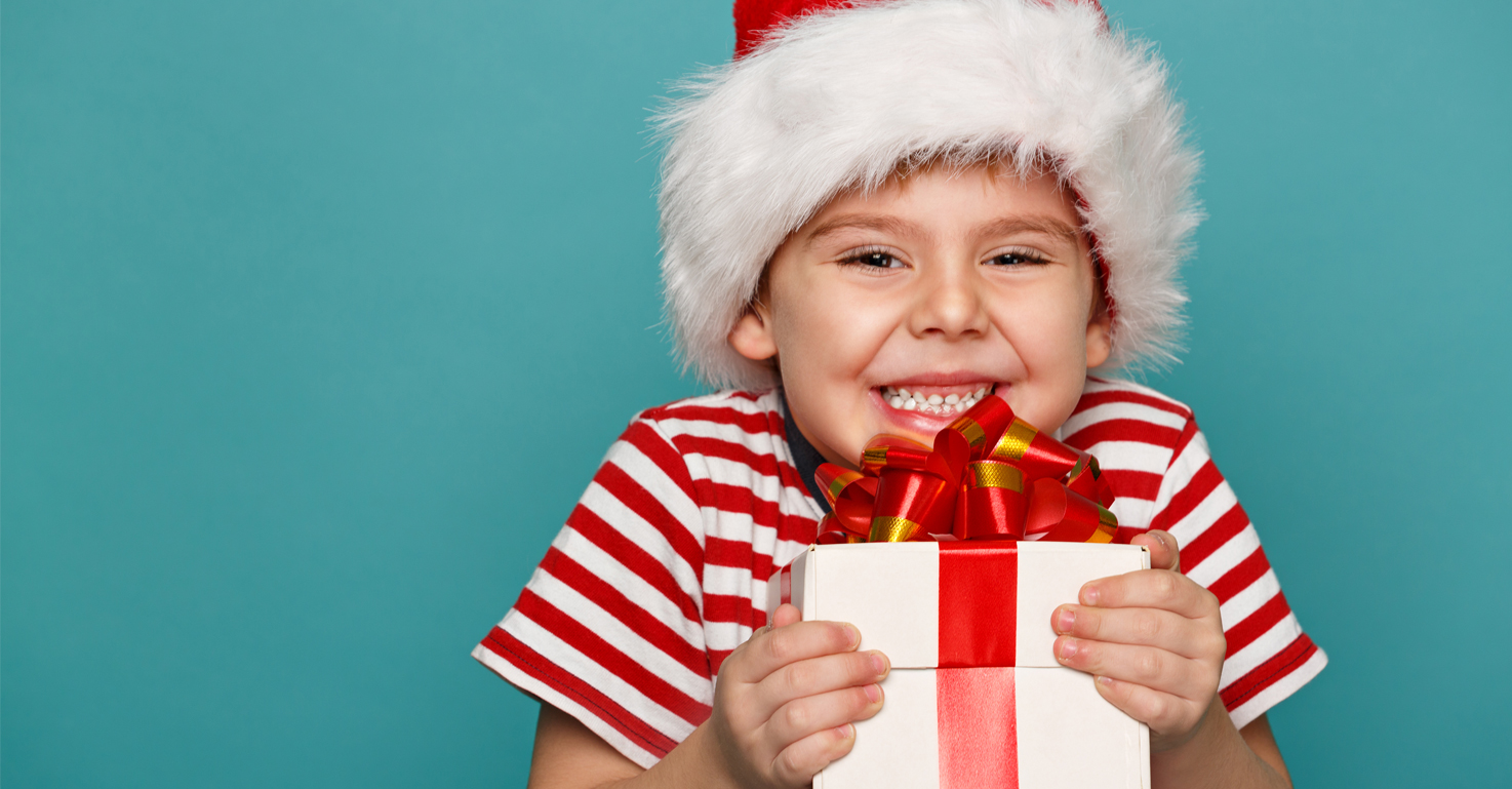 8.1--Peg-siling-funny-child-in-santa-red-hat-holding-christmas-gift-in-hand-christmas-concept